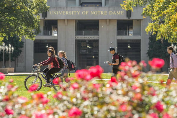 Students ride bikes and walk on a sidewalk on campus